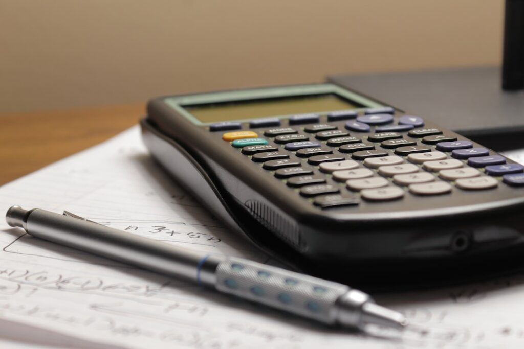 Calculator and pen on paper showing financial calculations